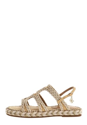 Sandalo piatto beige con cinturino intrecciato, punta aperta, cinturino regolabile alla caviglia e piccolo charm metallico sul lato.