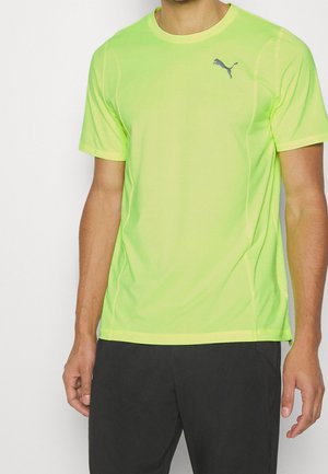 Koszulka sportowa z krótkim rękawem w fluorescencyjnym żółtym kolorze, wykonana z lekkiego materiału. Posiada niebieskie logo Puma na klatce piersiowej.
