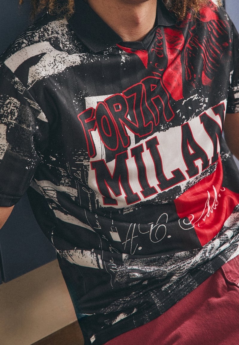 Polo shirt graphique noir et rouge arborant un audacieux texte "FORZA MILAN", des motifs abstraits et une texture lisse ; comprend un col noir.