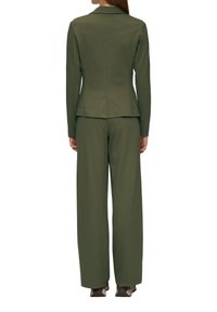 Traje entallado en verde oliva con mangas largas, chaqueta ajustada y pantalones de pierna ancha. Textura suave, diseño estructurado y sin patrones visibles.