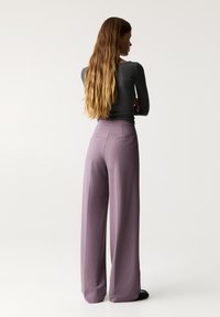 Pantalons taille haute, à jambes larges en tissu lavande doux avec une texture lisse. Comprend deux poches arrière et une coupe ajustée.