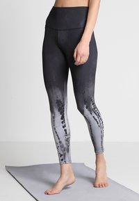 Czarne i szare legginsy z ombre, wysoki stan, gładka textura oraz abstrakcyjne wzory po bokach. Zaprojektowane do użytku sportowego.