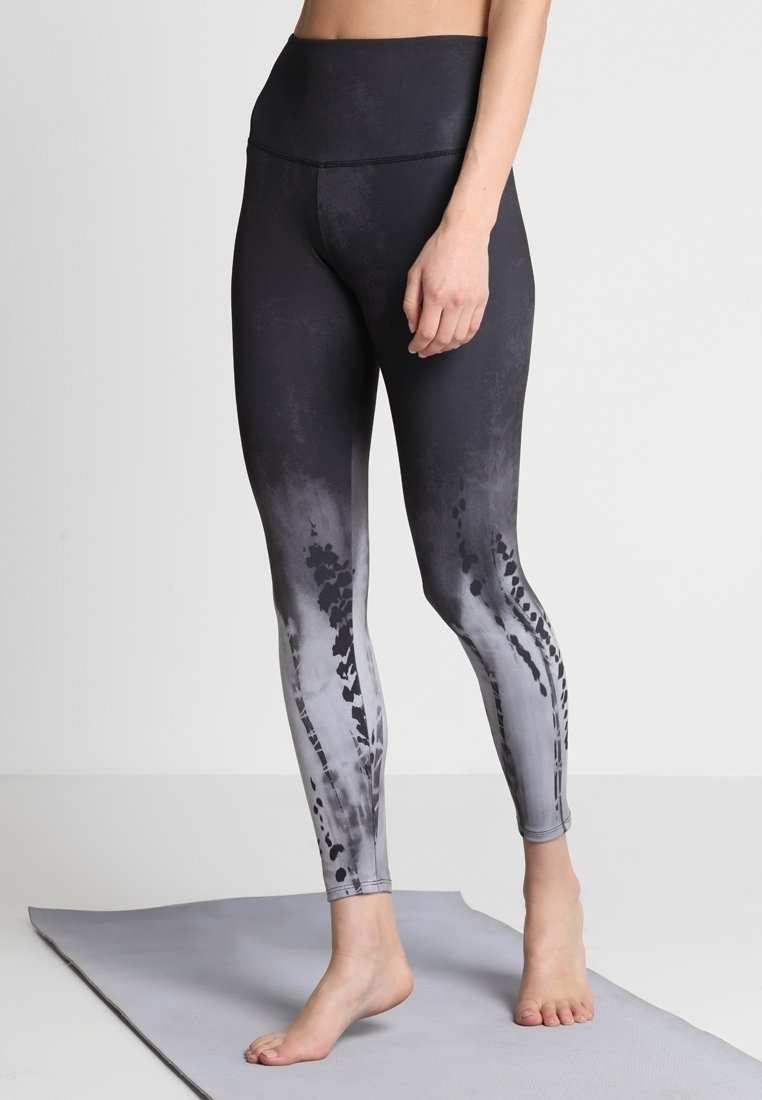 Czarne i szare legginsy z ombre, wysoki stan, gładka textura oraz abstrakcyjne wzory po bokach. Zaprojektowane do użytku sportowego.