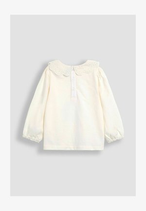 Krem dolgimi rokavi zgornji del z valovitim ovratnikom iz očesnega materiala, zapiranje na gumbih na hrbtu in naborki na manšetah. Mehak bombažni material, preprost dizajn.