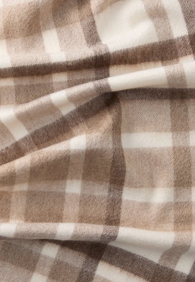 Brun og hvid plaid tæppe med en blød, fluffy tekstur, der har skiftende striber i forskellige nuancer af brunt og creme.