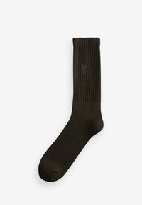 Braune gerippte Socke mit einem einfarbigen Muster, ausgestattet mit einem umgeschlagenen oberen Rand und einem leichten Glanz. Das Material wirkt glatt und weich, mit einem Logo-Akzent.