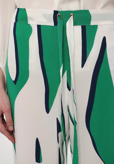 Pantalon en tissu à motifs verts et blancs avec des accents bleu marine, doté d'une taille à cordon de serrage et d'une texture lisse. Gros plan sur la ceinture.
