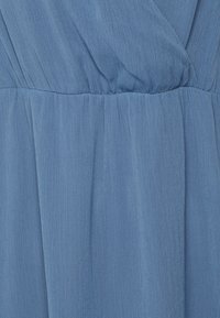 Sininen mekko, joka on valmistettu kevyestä, rypytetystä kankaasta, jossa on kootut vyötäröt ja sileä pinta. Mekossa on pehmeitä, valuavia laskoksia kauttaaltaan.