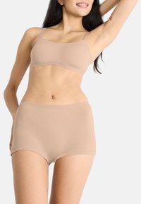 Beige sömlös bralette med justerbara band, matchad med hög midja trosor. Slät textur, åtsittande design.