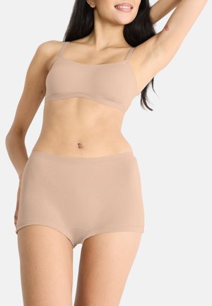 Beige sømløs bralette med justerbare stropper, parret med matchende højrschede trusser. Glat tekstur, tætsiddende design.