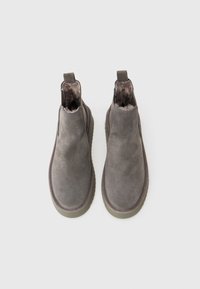 Γκρι σουέτ καπούτσια αστραγάλου με μαλακή υφή, στρογγυλή μύτη και ελαστικές πλευρικές πάντες. Εσωτερικά επενδεδυμένα με μαλακό υλικό, διαθέτοντας ανθεκτική καουτσούκ σόλα.