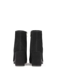 Botas de tobillo de ante negro con un alto tacón cuadrado y cremalleras laterales. El diseño presenta una textura suave y una silueta minimalista.
