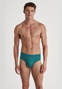 Herren-Schwimmbriefe in Türkis, mit einem geometrischen Muster und einer glatten Textur. Hoch geschnittenes Design mit einem bequemen Bund.