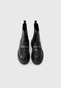 Black leather ankle boots with a chunky sole, featuring a wide strap labeled “VALENTINO” for detail. Smooth texture and sleek design.