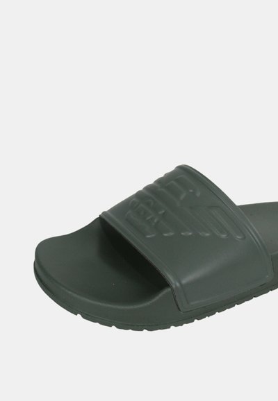 Infradito in gomma verde scuro con una larga fascia caratterizzata da un motivo testurizzato; suola piatta con una leggera curvatura per supporto del piede.