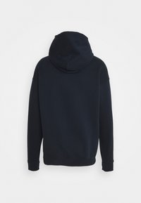 Felpa blu navy con cappuccio regolabile, maniche lunghe e polsini a costine. Texture liscia, design semplice e vestibilità rilassata senza loghi visibili.