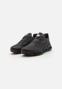 Black athletic shoes with a textured synthetic upper, rounded toe, and toggle lacing system. Features cushioning and a unique blue accent on the sole.
