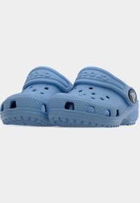 Γαλάζια παπούτσια τύπου slip-on με τρύπες αερισμού, υφή στην σόλα και ρυθμιζόμενα λουράκια στη φτέρνα με κυκλικό λογότυπο σε κάθε πλευρά.