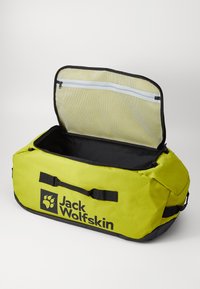 Gele sporttas met zwarte accenten, ritssluiting met gaasvak, grote opening en "Jack Wolfskin" logo. Gemaakt van duurzaam materiaal.
