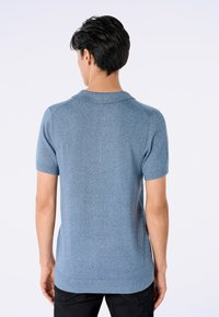 Camisa polo de manga corta para hombre en azul claro. Presenta un tejido de punto texturizado, cuello clásico y dobladillo recto. Diseño sencillo y práctico.