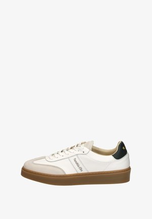 White leather sneaker with light beige accents, round toe, and tan rubber sole. Features black heel tab with gold star detail.
