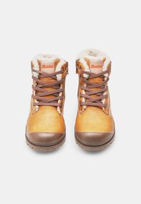 Kaksikud taupe värvi talvekingi, pruunide kummitaldadega, valge sünteetilise karvaga vooderdatud ja pruuni mustriga paelad, vaadatuna eest.