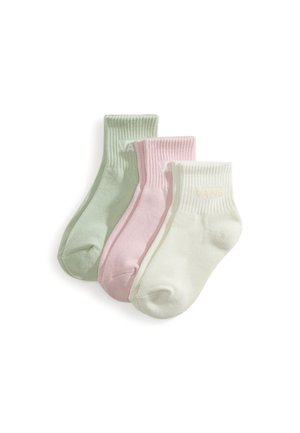 Tre ribbede ankelstrømper i pastelgrøn, lyserød og hvid arrangeret side om side på en hvid baggrund.