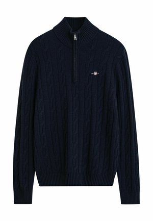 Marineblauer Kabelstrickpullover mit hohem Kragen und halbem Reißverschluss. Verfügt über gerippte Bündchen und Saum, hergestellt aus weichem Strickstoff. Logo auf der Brust.