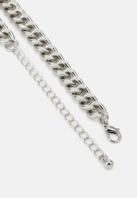 Bracelet en chaîne argentée chunky avec un fermoir mousqueton et une chaîne d'extension présentant un détail de perles rondes. Fini métallique poli.