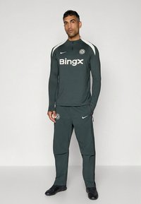 Tume roheline spordidress pika varrukaga, valgete detailide ja Bingxi logoga. Omaduseks on lukk kaelusel ja Chelsea FC vapp rinnal.