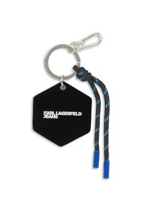 Portachiavi esagonale nero con "KARL LAGERFELD JEANS" in bianco. Presenta un anello in metallo argentato, un cordino intrecciato con accenti blu e punte in plastica.
