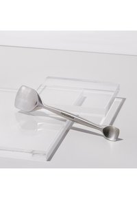 Spingi cuticole in acciaio inossidabile a doppia estremità con una punta piatta e una curva a cucchiaio su blocchi acrilici trasparenti.