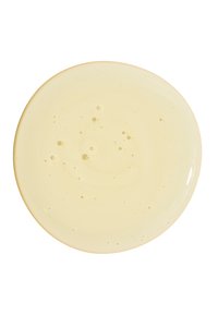 Cremige, blassgelbe Flüssigkeit mit kleinen Blasen, in einem runden, glatten Teller mit glänzender Oberfläche enthalten.