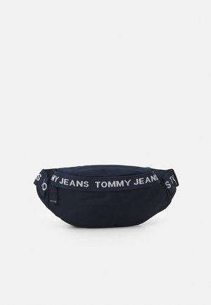 Granatowa nerka wykonana z trwałej tkaniny. Posiada szeroki pasek z napisem „TOMMY JEANS”. Zaokrąglony kształt z zamknięciem na zamek błyskawiczny.