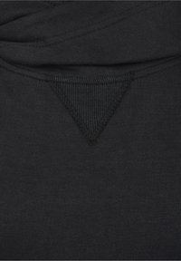 Tela de sudadera negra con textura acanalada, con un acento triangular en el cuello cosido con hilo negro. Diseño simple.