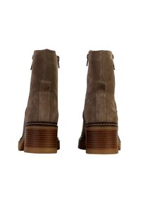 Suède enkellaarsjes in licht taupe met een gestapelde hak, voorzien van een rits aan de zijkant, contrasterende crème stiksels en een taps toelopende neus.