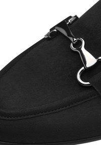 Zwarte suède schoen met een metalen zilveren haakaccent, ronde vorm en nette stiksels langs de randen.