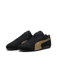 Scarpe da ginnastica nere realizzate in suede e mesh, con un'accennata curvatura dorata sul lato e lacci per una vestibilità sicura. Suola in gomma texturizzata.