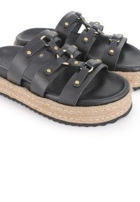 Sandalias deslizables de cuero negro con múltiples correas, tachuelas en tono dorado y una suela de plataforma de yute al estilo espadrille. Suela de goma texturizada.
