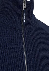 Marineblauer, gerippter Strickpullover mit hohem Kragen und Reißverschluss. Verfügt über ein DOVRE-Label in der Nähe des Reißverschlusses und eine glatte Textur an den Schultern.