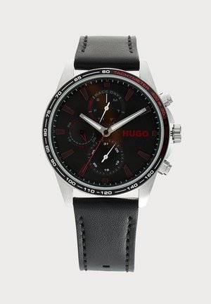 Schwarze runde Hugo-Armbanduhr mit silbernem Gehäuse, drei Subdials, Tachymeter-Lünette und schwarzem Lederarmband mit sichtbarer Naht.
