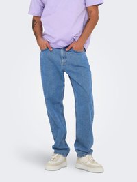 Heled lillat värviline puuvillane T-särk, lõdva istuvusega, koos siniste teksadega, sirge jala lõikega, ja kreemivärvi retro disainiga spordijalatsitega.