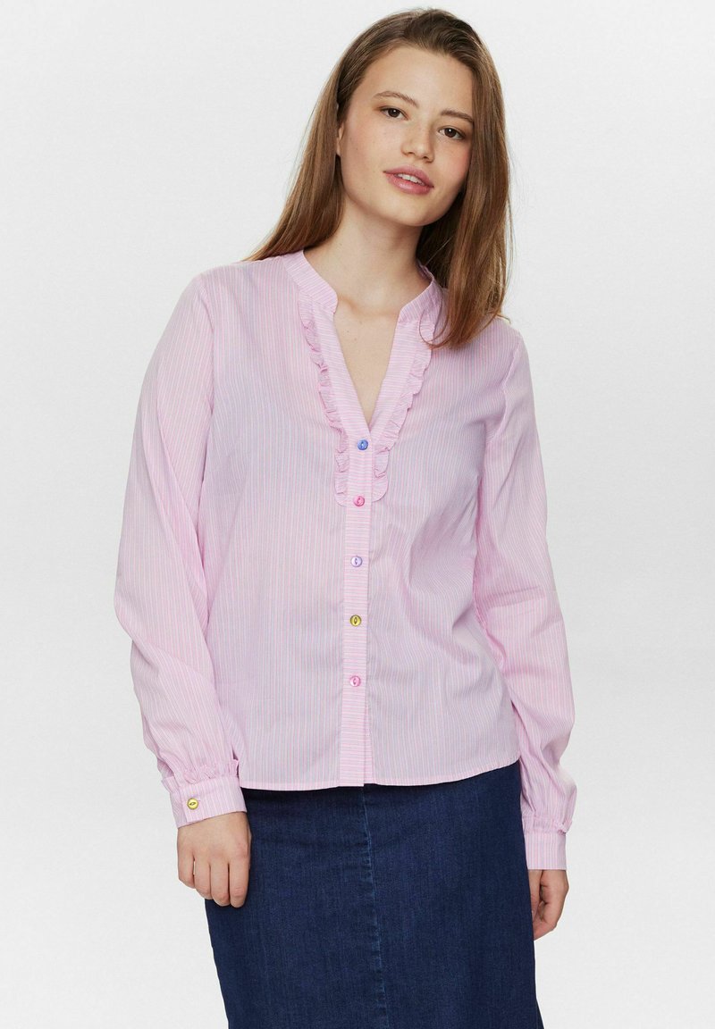 Camicia button-up rosa chiaro con righe verticali bianche, scollatura a V arricciata e bottoni colorati. Tessuto morbido con maniche lunghe.