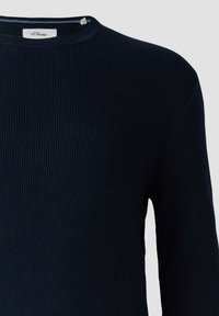 Ciemnoniebieski sweter o teksturowanym splocie z okrągłym dekoltem i widoczną metką marki s.Oliver wewnątrz kołnierza.