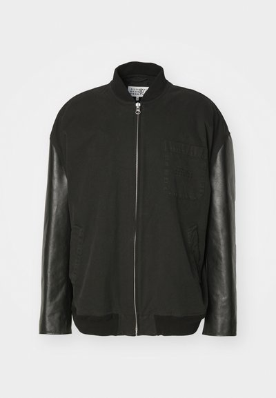 Μαύρο bomber μπουφάν με βαμβακερό σώμα, δερμάτινα μανίκια, εμπρόσθιο φερμουάρ και τσέπη στο στήθος με διακριτική λεπτομέρεια σχεδίου.