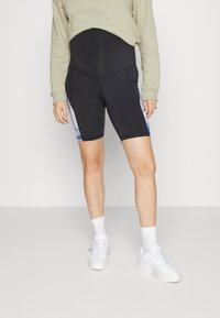 Calções de ciclismo pretos altas com um padrão gradual azul de lado, feitos de um material elástico, combinados com ténis brancos e meias.
