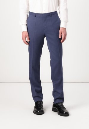 Bukser i en dyp blå stoff med en jevn tekstur, slim fit-design, sidelommer og pressfold, kombinert med svarte dressko.