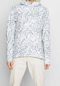 Blommönstrad lättviktsjacka i dämpade pasteller, med framsida dragkedja, huva och långa ärmar. Slät, vattenavvisande tyg.