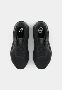 Chaussures de sport noires avec une tige en maille texturée, des lacets plats, des détails de logo et des semelles rembourrées. Conçues pour le confort et le soutien.