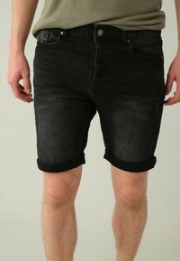 Shorts en denim noir avec un léger délavage, ourlets retroussés, cinq poches et fermeture à bouton en métal. Texture douce et coupe standard.